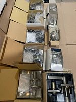 Multiple open boxes showing satin nickel and matte black door handle sets with hardware