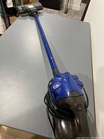 Full view of blue handheld stick vacuum with wand attached
