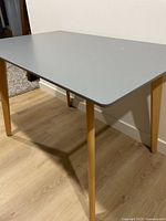 Full view of table showing gray top and wood legs