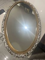 Full view of oval mirror showing gold inner and silver textured outer frame