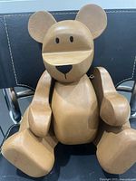 Front view of solid wood bear seated on chair