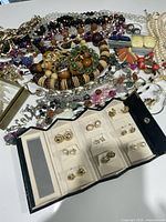 Pile of assorted necklaces, bracelets, brooches and earring organizer