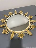 Full view of round mirror with sunburst leaf frame