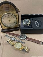 Group shot of mantel clock, wristwatches, multi-tool