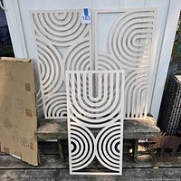 Three white wood panels with packaging visible