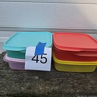 Stack of four square Tupperware containers in different colors