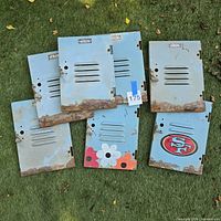 All seven locker doors laid out on grass showing rust and painted designs