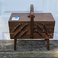 Closed wood accordion sewing box showing exterior and legs
