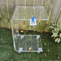 Full front view of acrylic C-shaped table showing casters