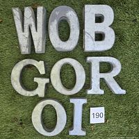 Front view of all eight galvanized letters arranged on grass