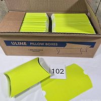 Open Uline case showing two stacks of lime green flat pillow boxes plus two assembled examples