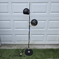Full view of floor lamp showing two black globe shades, chrome pole, round base and foot pedal