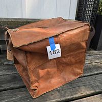 Collapsed tan leather ottoman cover showing exterior, edge trim and zipper pull