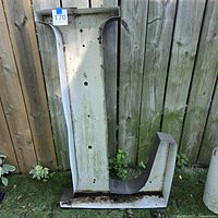 Front view of large metal channel letter L leaning against fence