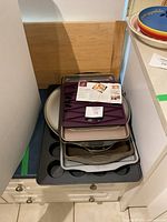 Stack of assorted metal and silicone bakeware pieces on cabinet