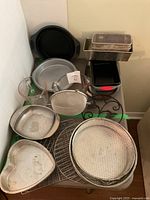 Overall view of lot showing mix of bakeware and kitchenware items on table