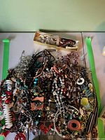 Overview of large pile of necklaces, chains, beads, and small box of findings