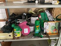 Overall view of shelf showing greenhouse kit, sprayer, solar lanterns, pruners, gloves, insecticide, kneeling pad, watering wand and ceramic containers