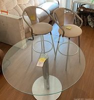 Round glass table top, metal base and two stools placed on top