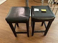 Front view of both bar stools showing vinyl seats and wooden legs