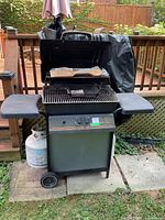 Front view of Silver Chef grill showing propane tank, side shelves and cover draped behind