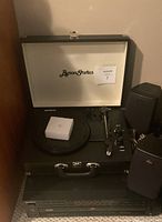 Byron Statics turntable open on top of Sony CD player with speakers beside