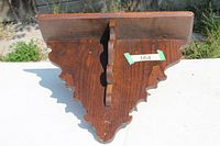 Front view of wooden clock shelf showing scalloped edges and support brace