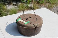 Overall view of rusted cast iron Dutch oven with lid and bail handle