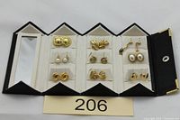 Full view of open black jewellery box displaying all nine earrings