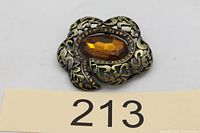 Front view showing ornate frame and amber center stone