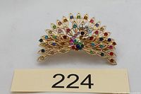Front view of gold-tone peacock hair clip showing multicolour rhinestones