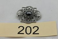 Front view showing ornate filigree design and black cabochon