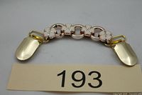 Front view showing white enamel flower motifs and gold-tone clips