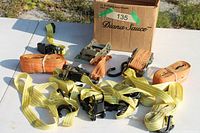 Collection of yellow and orange ratchet tie-down straps with hooks displayed on table