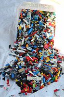 Open plastic tub spilling a large volume of multicolored loose LEGO pieces
