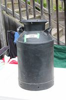 Full view of black milk can standing upright on table