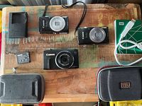 All items laid out: three Canon cameras, charger, battery, WD case, WD cable and box