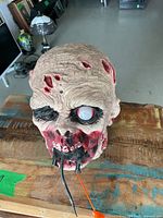 Front view of animatronic zombie skull prop showing eye, rat, and tongue