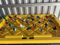Full group of miniature glass birds on yellow lid