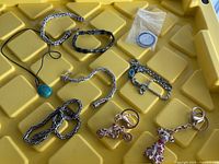 Overview showing all jewelry pieces, keychains and coin spread on yellow surface