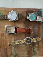 All four wristwatches on wooden surface
