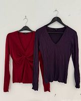 Front view of both Gucci knit tops on hangers