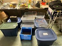 Wide view of multiple plastic totes, blue open crate, two metal wire baskets, lunch pail