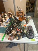 Table of assorted carved and ceramic bird figures, ducks and loons visible