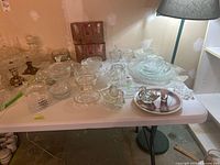 Tabletop view of the full pressed-glass assortment with candy dishes, bowls, platters and ashtrays.