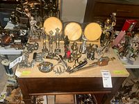Wide view of table with multiple metal figurines and glass jars on stand