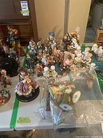 Wide view of table with large grouping of assorted figurines and bagged nativity pieces