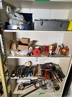 Four shelves showing metal toolboxes and assorted hand tools