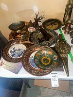 Overview showing chargers, bellows, bowl, deer figurine, frame, stein, candlestick