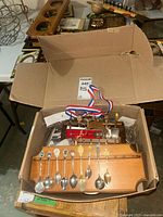 Open box showing wooden spoon rack with spoons hanging, additional racks beneath